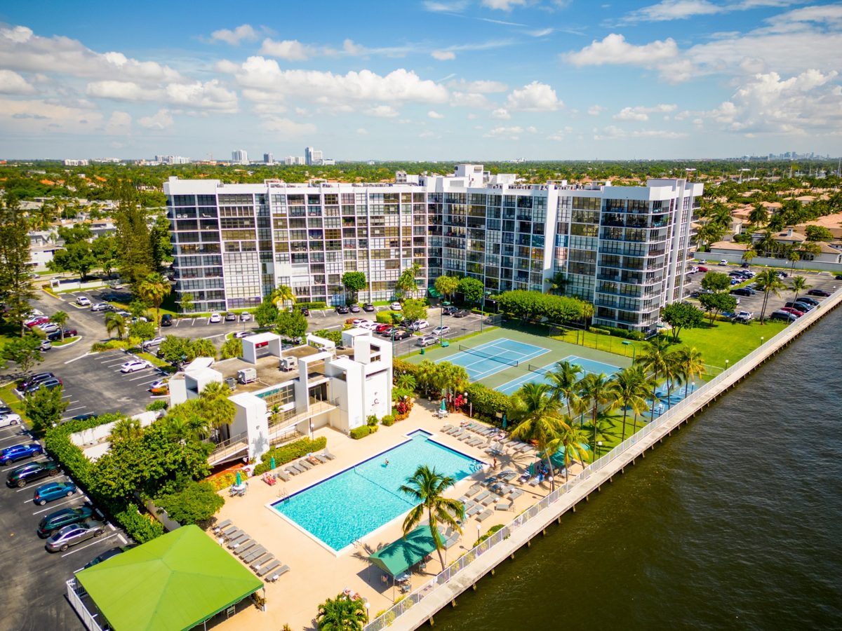 Aerial view of a waterfront condo building with pool and tennis courts on the Intracoastal